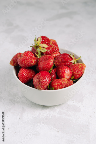 Fresh strawberries in a plate on a white background  healthy food and vitamins for vegetarians and healthy happy people  diet. Beautiful berry from the garden. Vertical photo with place for text.