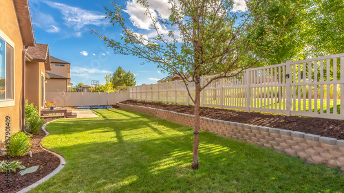 фотографія Panorama frame Home backyard with vibrant lawn and raised planting bed along whi