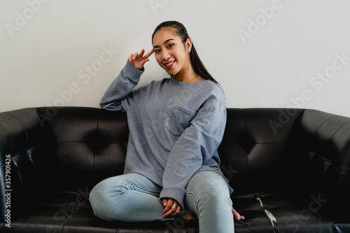 The girl with a light blue sweatshirt works at home. Sitting on the black sofa. Interior, house.