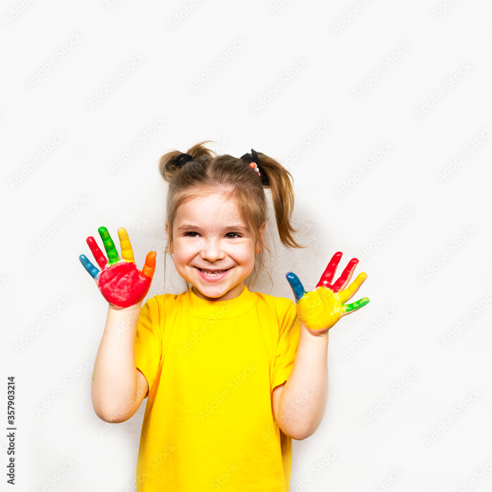 Beautiful little girl with hands in paint smiles in a yellow T-shirt. Children's creativity. Beautiful little girl with hands in paint smiles in a yellow T-shirt. Children's creativity.