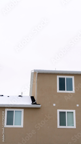 Vertical frame Exterior view of building with snowy pitched roof over wall with sliding windows