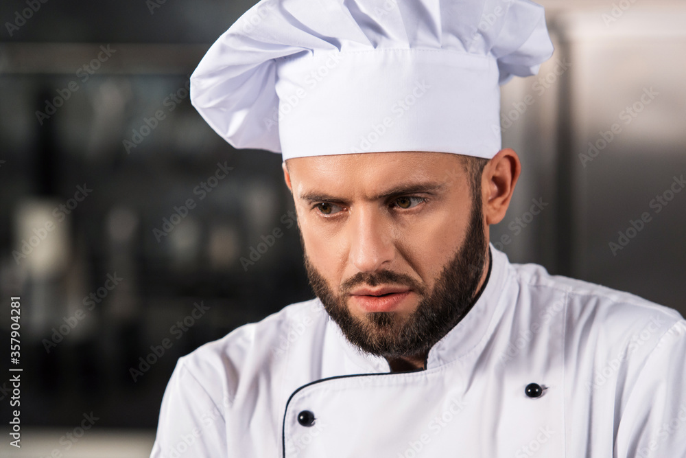 Chef man portrait at professional kitchen. Serious chef in uniform at kitchen.