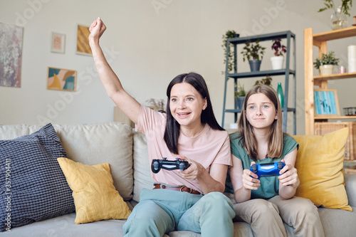 Εκτύπωση καμβά Excited mother winning video game while her distraught daughter looking with sad