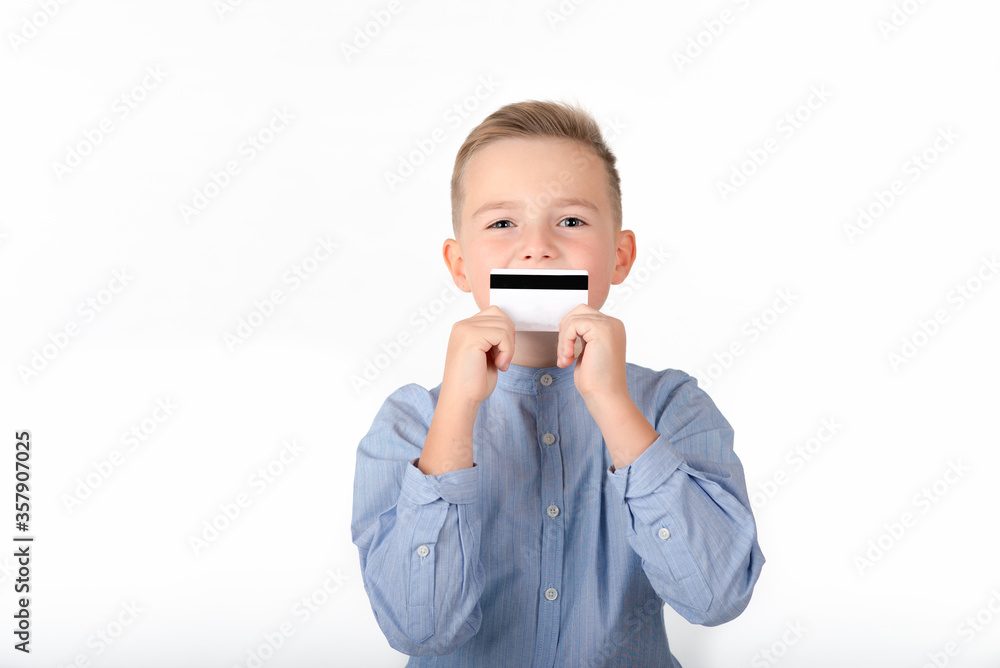 blonde caucasian cute boy in blue shirt holding credit card.picture isolated on white background. blonde caucasian cute boy in blue shirt holding credit card.picture isolated on white background.
