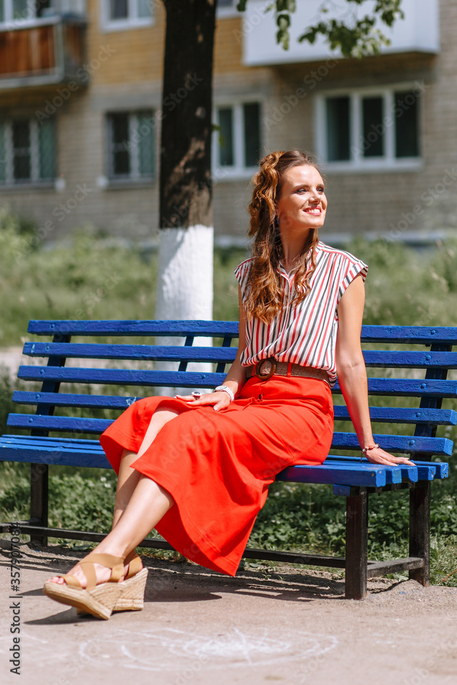 Model in a red skirt and striped blouse, on the street
