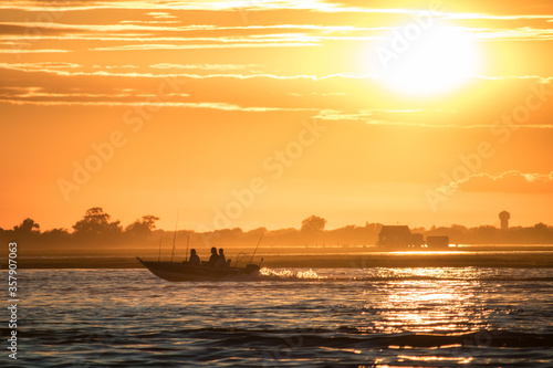 Small fishing boat returning as the sun sets behind it. Long Island NY