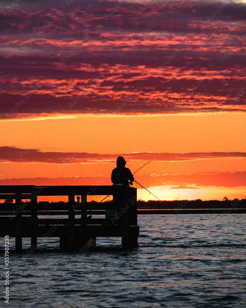 Silhouette of a man fishing on the Field 10 piers at Jones Beach State Park at sunset. Long Island