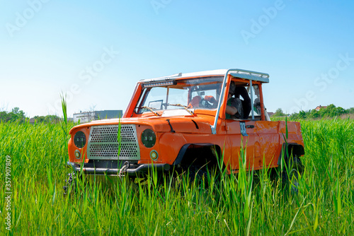 Rostov-on-Don, Russia, 06/07/2020. Off-road orange SUV car stands in the dense green grass