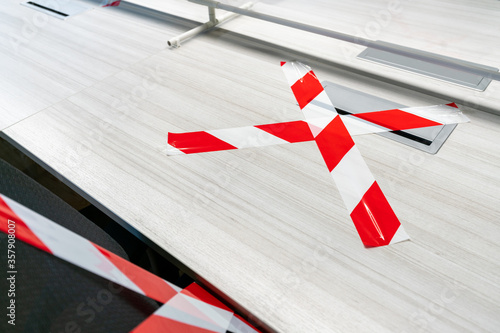 Office table marked with white and red tape and the plastic physical wall. Concepts for social distancing in offices during the Covid-19 pandemic. Precaution and safe workspace.