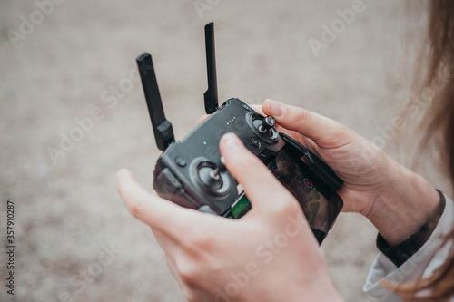 The girl holds a drone controller in her hands. The girl controls the drone. Hands and controler close-up.