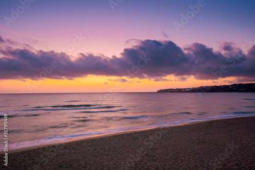 sea scenery at sunset. beautiful landscape of sandy beach in purple dusk. wave running on to the shore. clouds on the  sky above horizon.