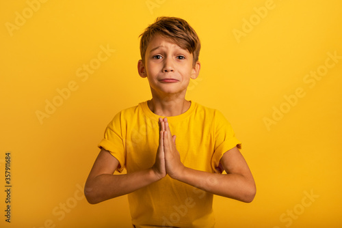 Child is pleading because he has something to request. Yellow background photo