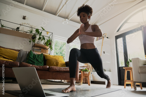 Canvas Print Wide angle shot of young female doing home workout or yoga from home, following