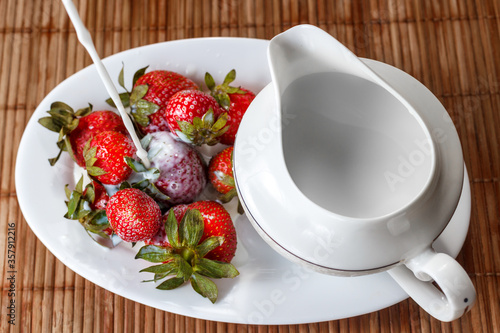 Strawberries are poured with cream on a tray with milk jug