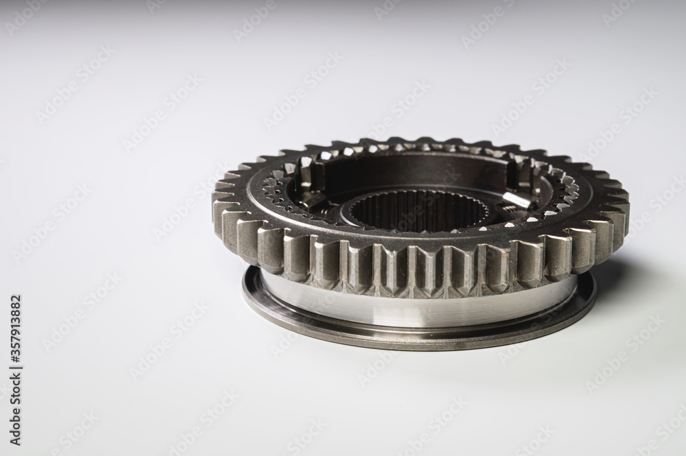 The new shiny metal gear of the switch box is fronted by a gray gradient background. The concept of new spare parts for car maintenance and repair The new shiny metal gear of the switch box is fronted by a gray gradient background. The concept of new spare parts for car maintenance and repair