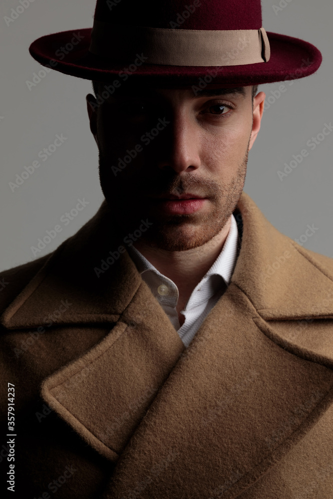 young smartcasual man wearing hat and long coat young smartcasual man wearing hat and long coat