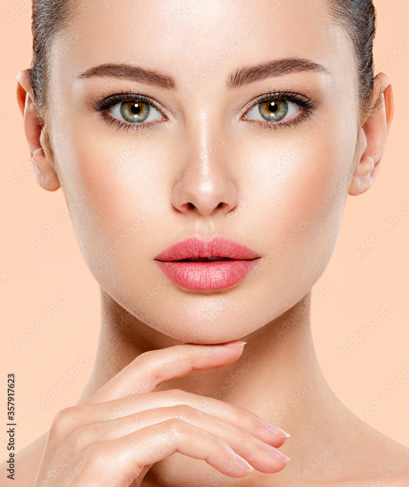 Fototapeta premium Portrait of beautiful girl which touching her fresh face. Closeup face of young woman with clean skin. Skin care.
