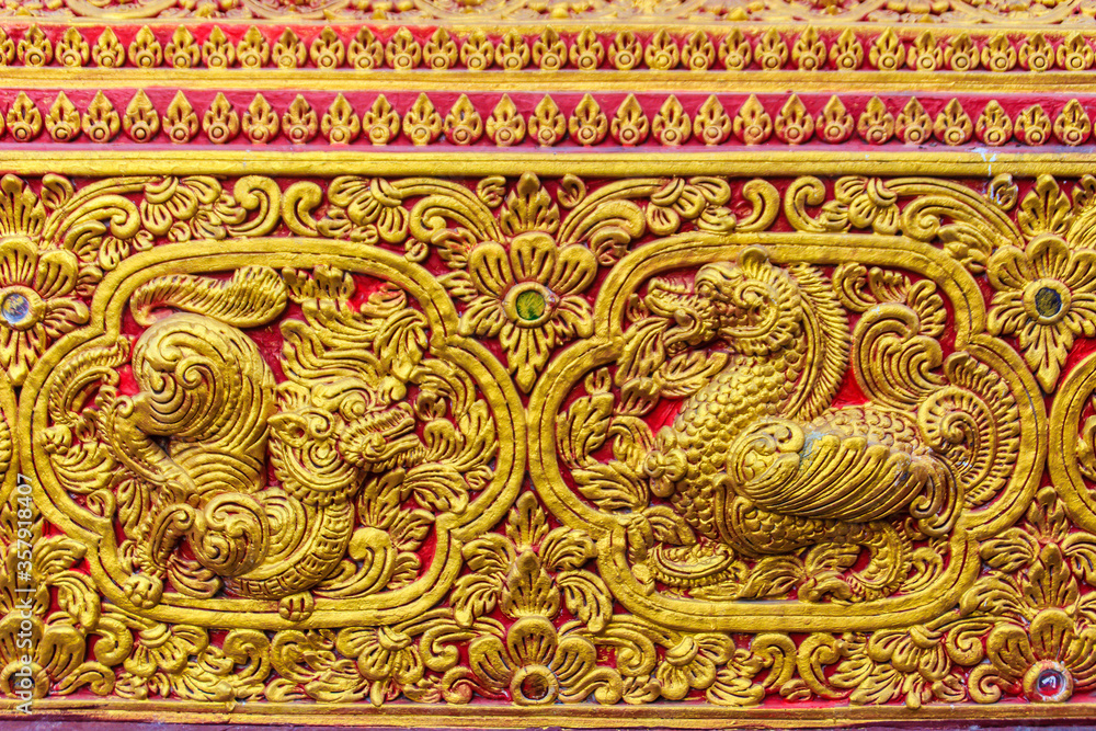 Beautiful golden carving of the mythical singha or lion on the sanctuary Buddhist church wall at Wat Srisupan, Chiang Mai, Thailand.