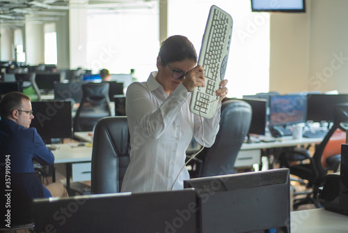 Photo A woman freaks out and gets depressed from a mistake and breaks the keyboard on the monitor