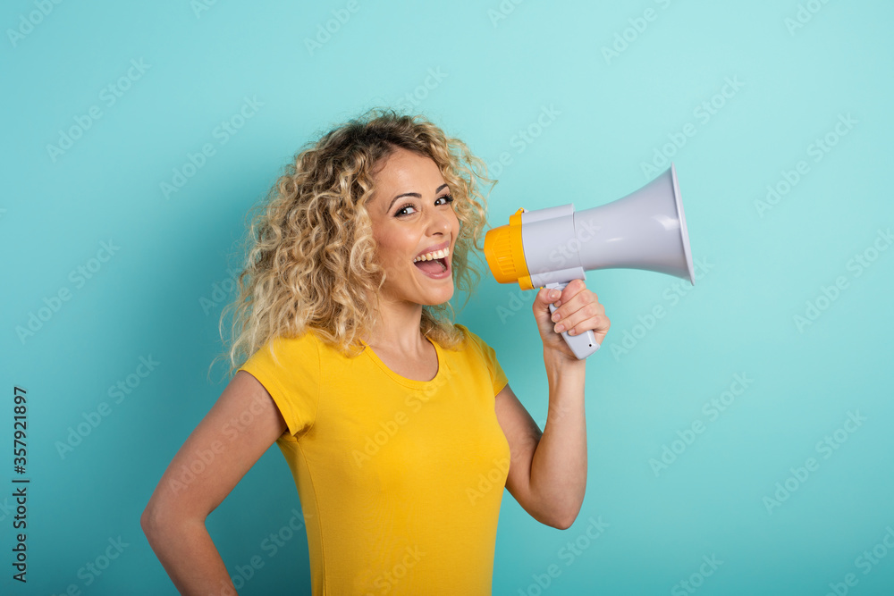 Woman speaks with loudspeaker. joyful expression. cyan background Woman speaks with loudspeaker. joyful expression. cyan background