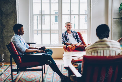 Foto Black man listening intently and sitting with crossed leg in chair on meeting