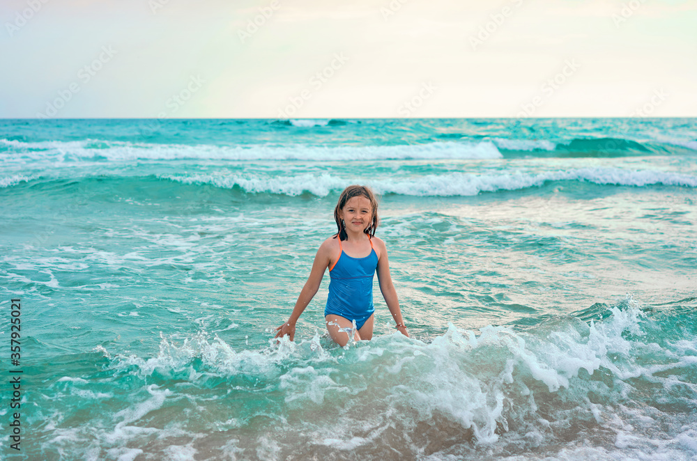 little girl sitting on the beach by the water Stock Photo | Adobe Stock