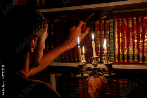 Boy holding book from the library in the dark with candles to light his way