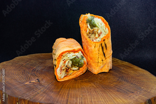 Shawarma  fresh roll of lavash, chicken beef shawarma falafel, grilled meat, mushrooms, cheese. Traditional Middle Eastern snack. On wooden background. photo