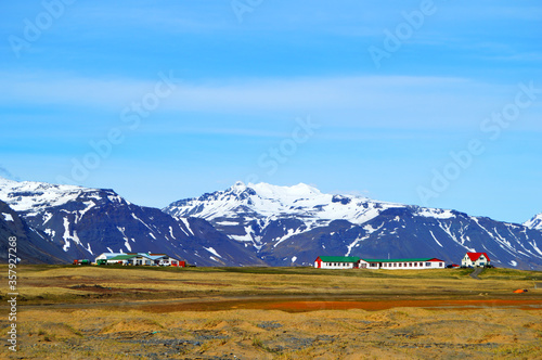 Isolated houses on top of a hill and snowy mountain chain as backgroung