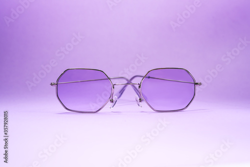 Beautiful sunglasses laying on the purple background. Concept photo for your projects.