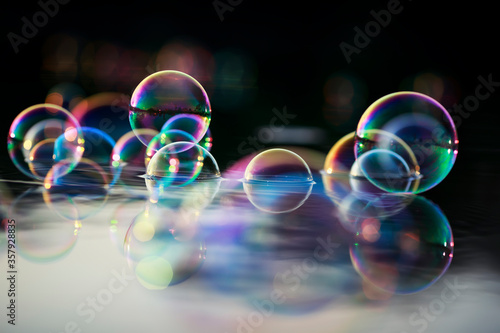 background with many sparkling iridescent soap bubbles float on the water and are reflected in the rays of the sunset