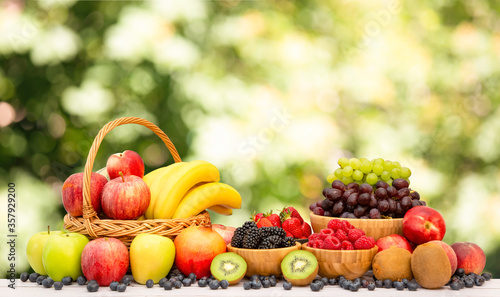 Fototapeta Naklejka Na Ścianę i Meble -  Group Healthy fresh fruit in a wooden basket, With vitamins c from bananas, kiwi, grapes, raspberries, blueberries, and blackberries, good for the body and diet food on the table in nature background.