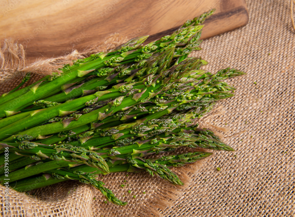 Bunches Fresh green asparagus on burlap and on a board. top view - image. High quality photo Bunches Fresh green asparagus on burlap and on a board. top view - image. High quality photo