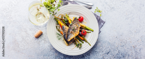 Photography top view of delicious fish with vegetables on white plates and wine glasses on g