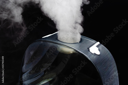 Humidifier on a black background. Humidifier overall plan and macro. The device is face and sideways. Steam water in macro. Black navigation bar, humidifier controls white touch mode keys