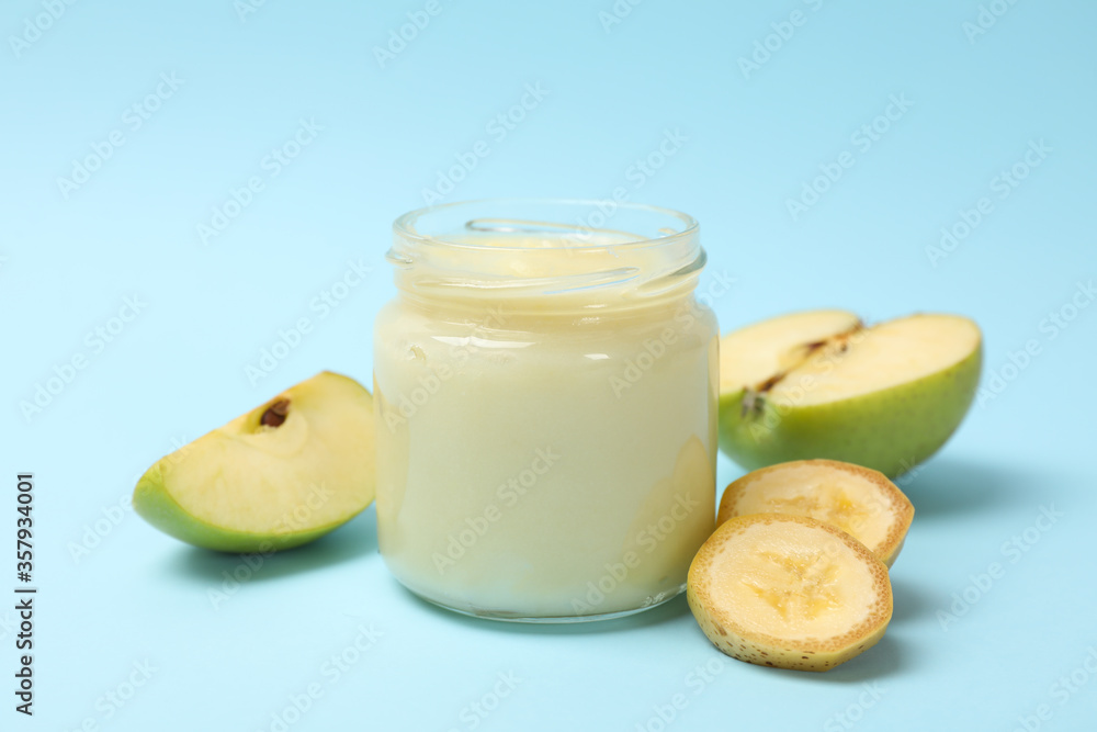 Glass jar with apple puree on blue background, close up Glass jar with apple puree on blue background, close up