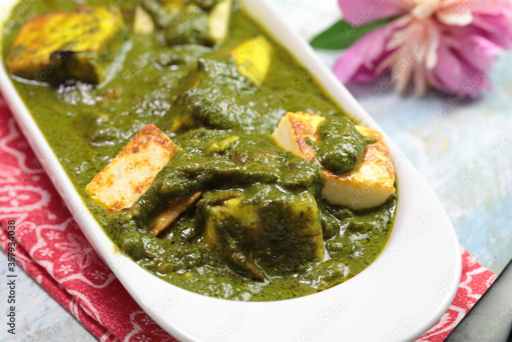 A bowl of Palak Paneer made of Paneer cheese dipped in mildly spiced Spinach gravy. A bowl of Palak Paneer made of Paneer cheese dipped in mildly spiced Spinach gravy.