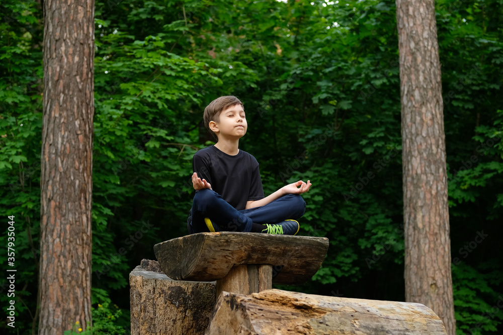 Fototapeta premium Child yoga in park. Young boy in yoga position close his eyes and meditate.