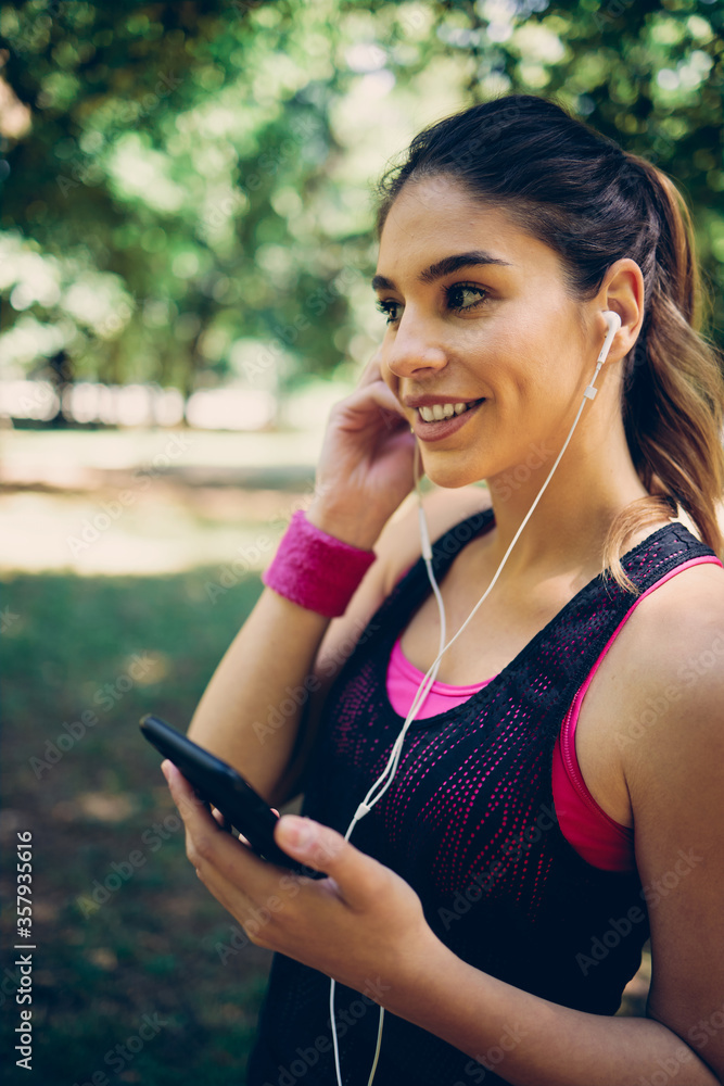 Beautiful caucasian sportswoman standing and using smart phone in nature. Beautiful caucasian sportswoman standing and using smart phone in nature.