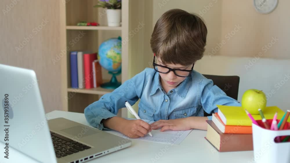 Online distance education learning lesson concept. Child Boy Kid schoolboy in glasses using tablet laptop computer for school homework, studying at home. Coronavirus COVID-19 quarantine, 4 K slow-mo Online distance education learning lesson concept. Child Boy Kid schoolboy in glasses using tablet laptop computer for school homework, studying at home. Coronavirus COVID-19 quarantine, 4 K slow-mo