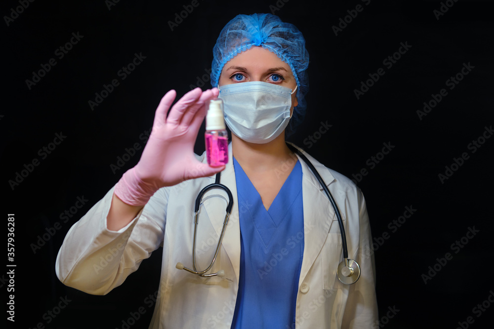 Doctor in a medical mask with hand sanitizer, copy space. A nurse holds a disinfectant in her hand on a black background. Concept of medical work in the coronavirus epidemic Doctor in a medical mask with hand sanitizer, copy space. A nurse holds a disinfectant in her hand on a black background. Concept of medical work in the coronavirus epidemic