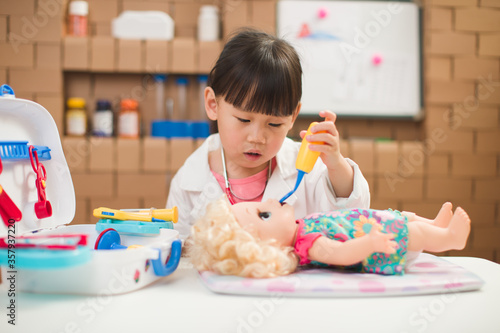 Bild auf Leinwand toddler girl pretend play doctor role  at home