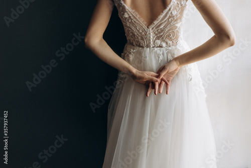 gentle hands of a young woman behind her back. hands of the bride on a white dress