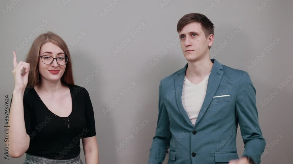 Hand points index finger up, pointing forefinger surprise gift option, great idea. Young attractive couple boyfriend girlfriend two people, dressed black t-shirt, blue jacket, grey background Hand points index finger up, pointing forefinger surprise gift option, great idea. Young attractive couple boyfriend girlfriend two people, dressed black t-shirt, blue jacket, grey background
