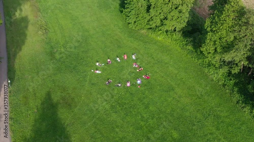 a group of people doing yoga on a meadow outside the city. filmed with a drone photo