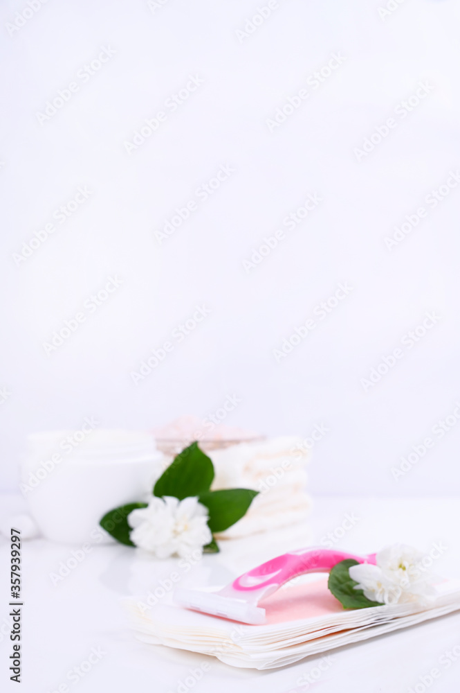 a set of different means for epilation on a colored background. Removal of unwanted hair. Body care products, towels, jasmine flowers, wax strips, razor. Minimalism. flatlay