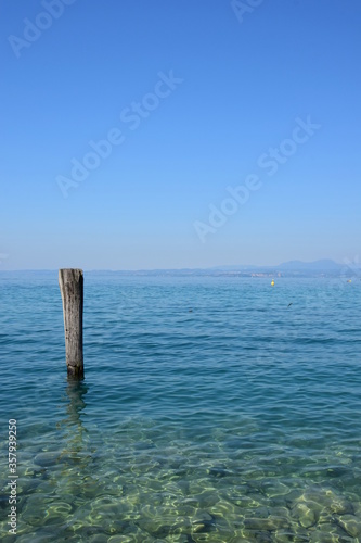 Holzpfahl im Wasser als Anlegestelle für Boote und Schiffe am Gardasee in den Sommermonaten