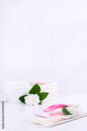 a set of different means for epilation on a colored background. Removal of unwanted hair. Body care products, towels, jasmine flowers, wax strips, razor. Minimalism. flatlay