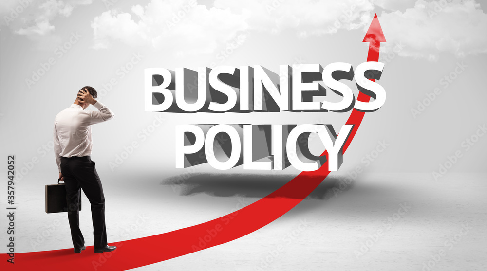 Rear view of a businessman standing in front of BUSINESS POLICY inscription, successful business concept Rear view of a businessman standing in front of BUSINESS POLICY inscription, successful business concept
