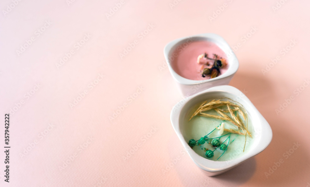 Minimalistic composition with two handmade candles in blue and pink lying on a blue paper square. Objects on a light pink background with paper texture. Handmade candles concept made from natural Minimalistic composition with two handmade candles in blue and pink lying on a blue paper square. Objects on a light pink background with paper texture. Handmade candles concept made from natural